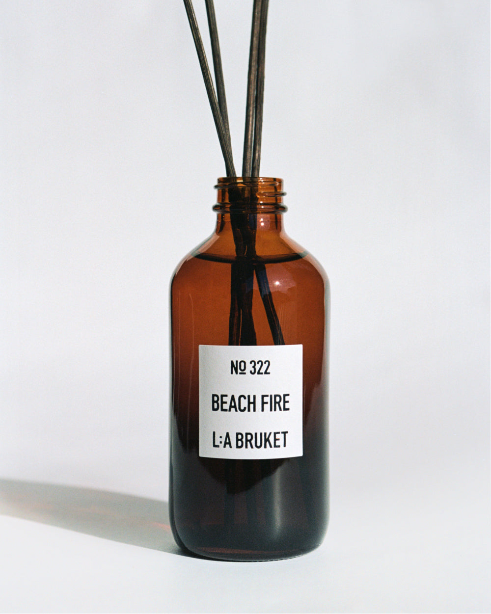 L:A BRUKET No 322 Beach Fire room diffuser in amber glass with reeds